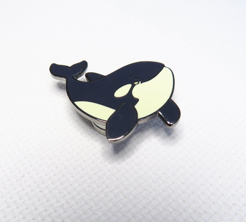 Orca whale-shaped pin on a white background