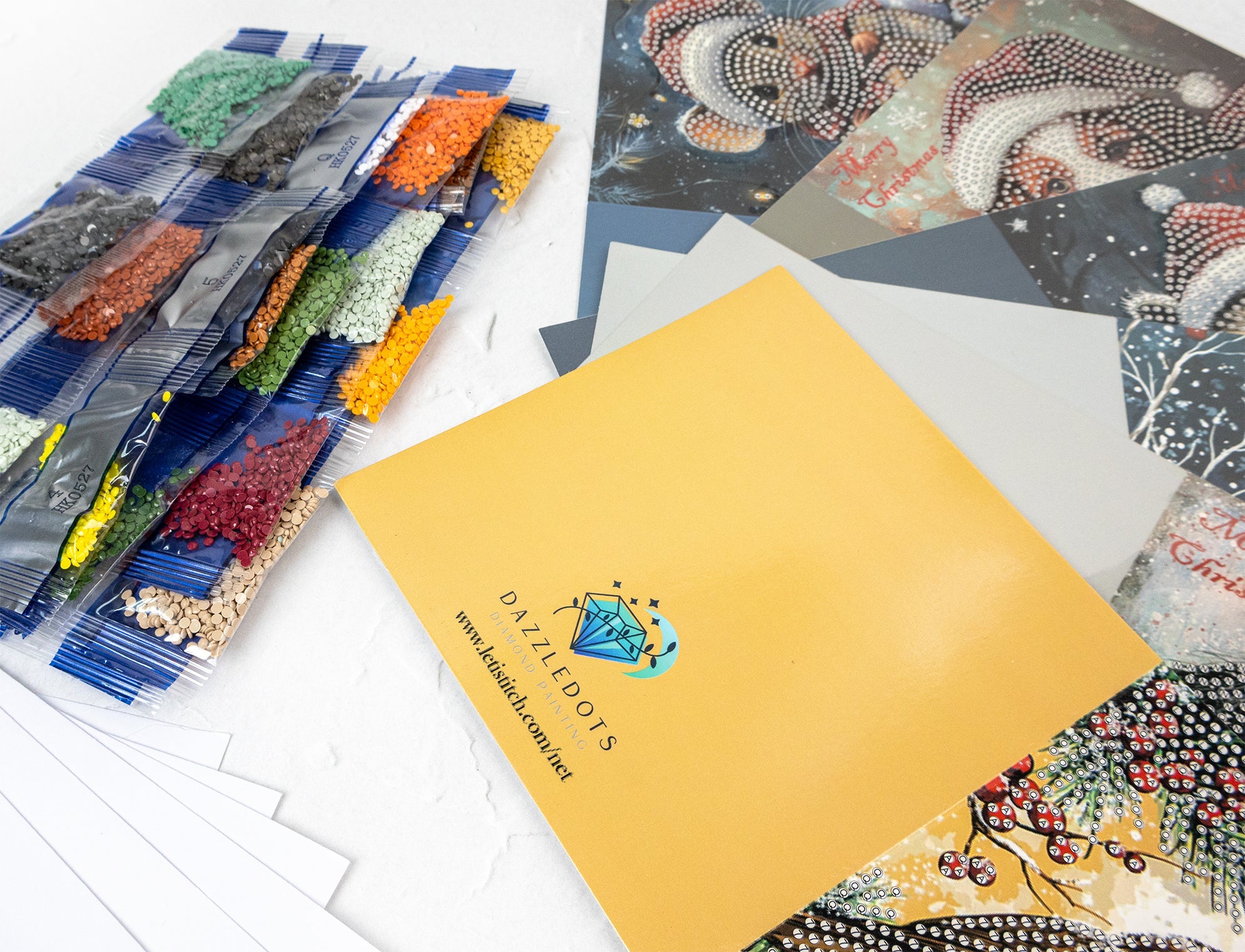 Collection of colorful art pieces and a yellow sheet with 'Dazzledots' branding on a white surface.