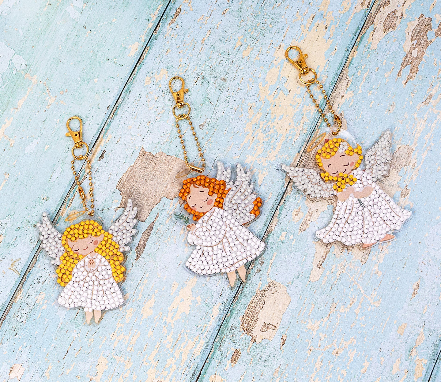 Three angel keychains on  a textured blue surface