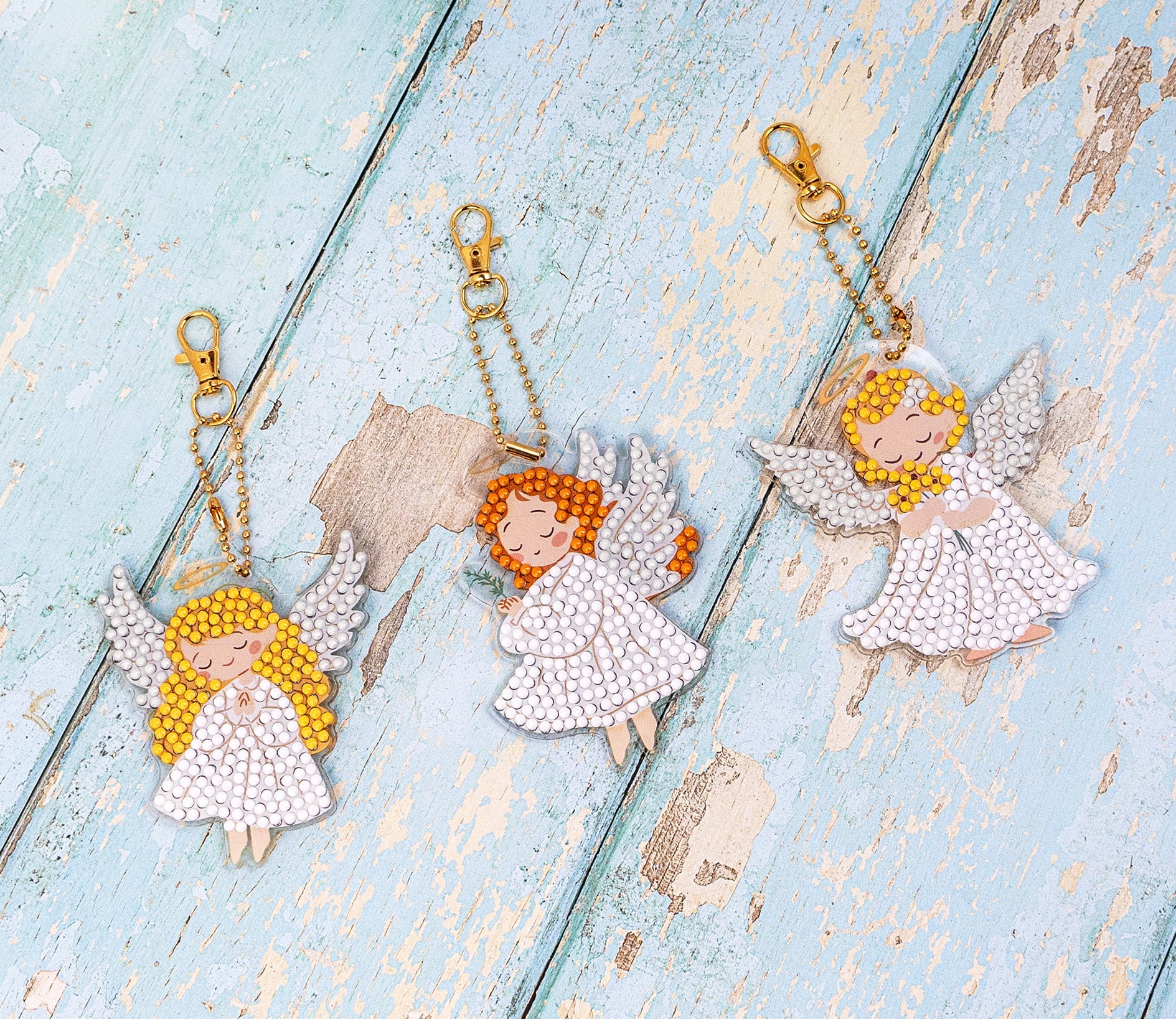 Three angel keychains on  a textured blue surface