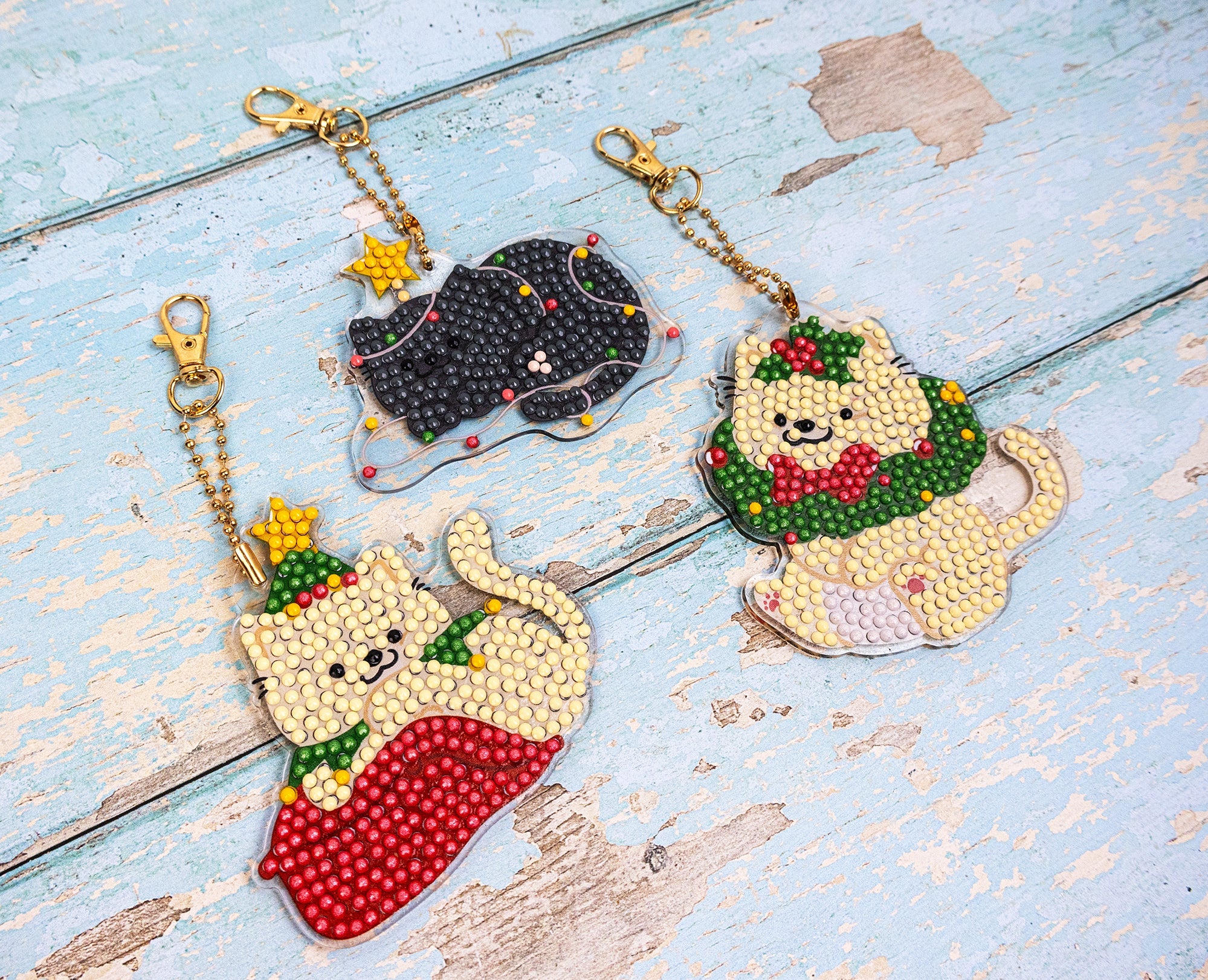 Four cat-shaped keychains with festive designs on a rustic wooden surface.