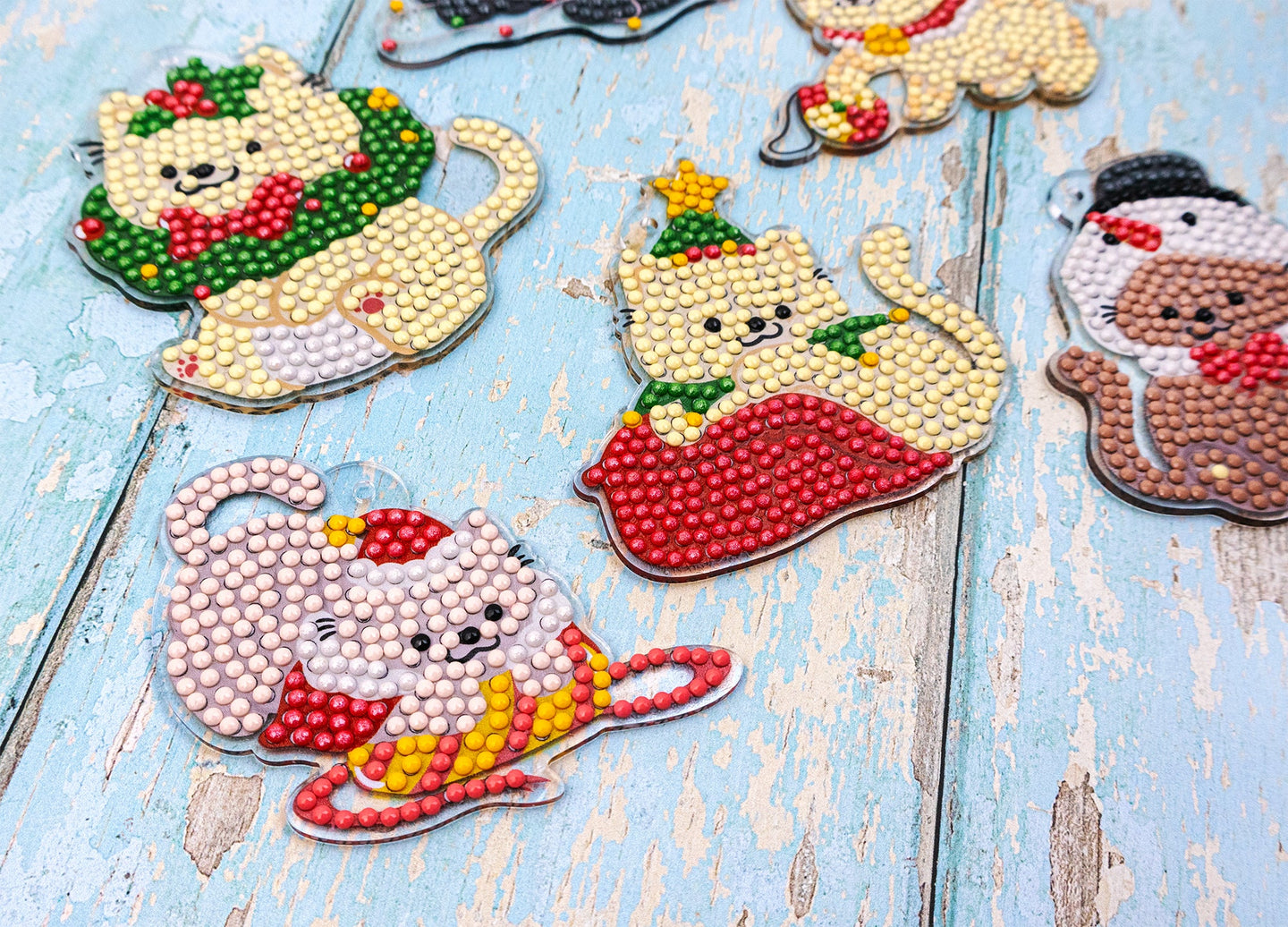 Decorative Christmas-themed cat figurines made with beads on a wooden surface.