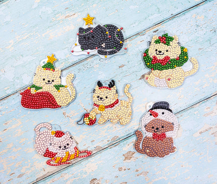 Decorative cat figurines with festive accessories on a light blue wooden surface