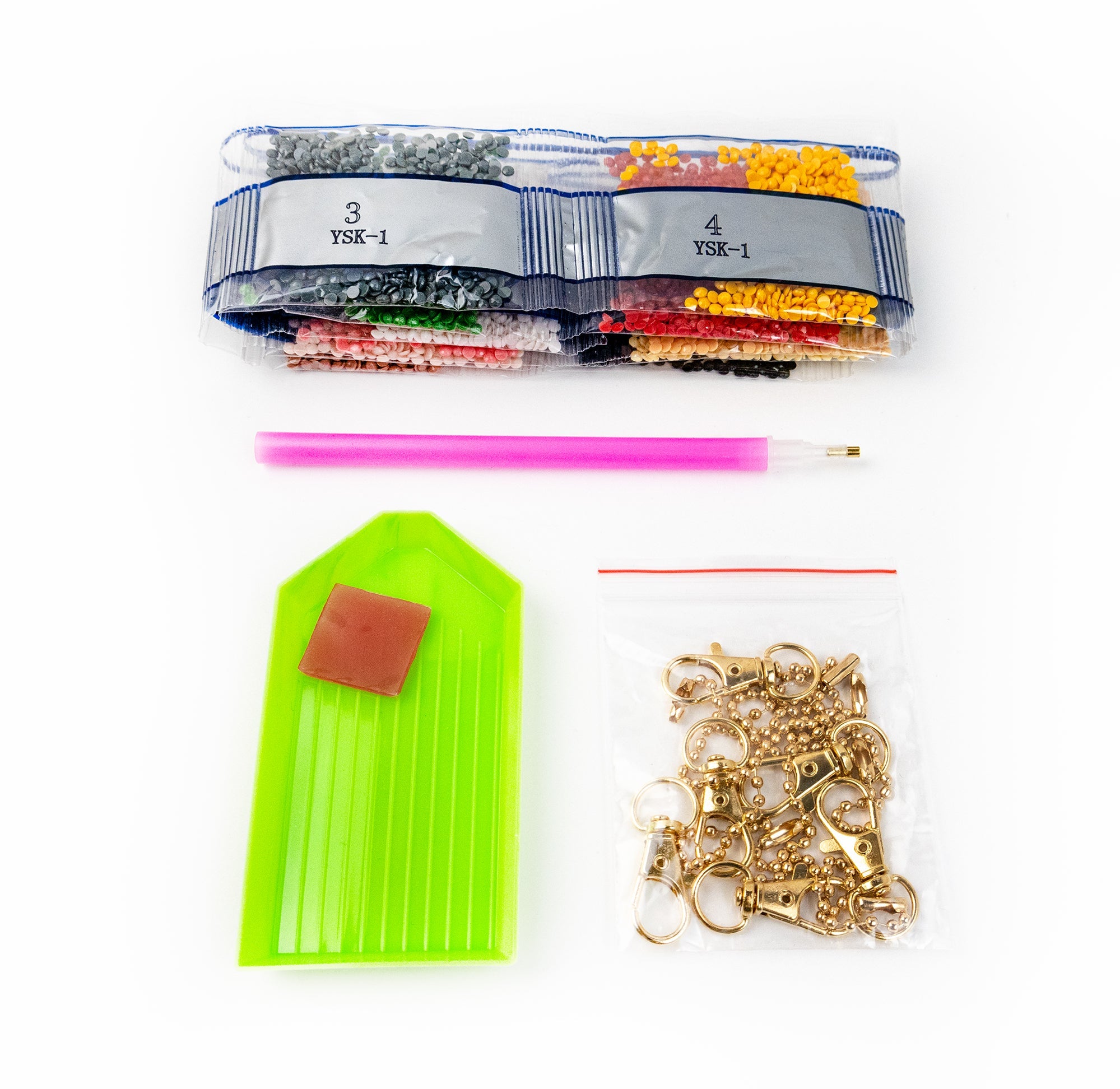 Assorted jewelry-making supplies including beads, a green tool, and gold chains on a white background.