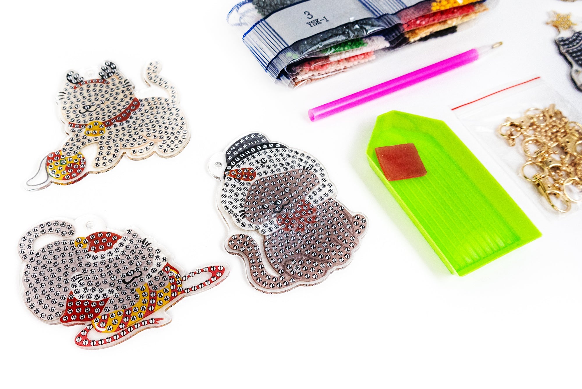Decorative cat designs made with beads on a white surface with craft supplies.