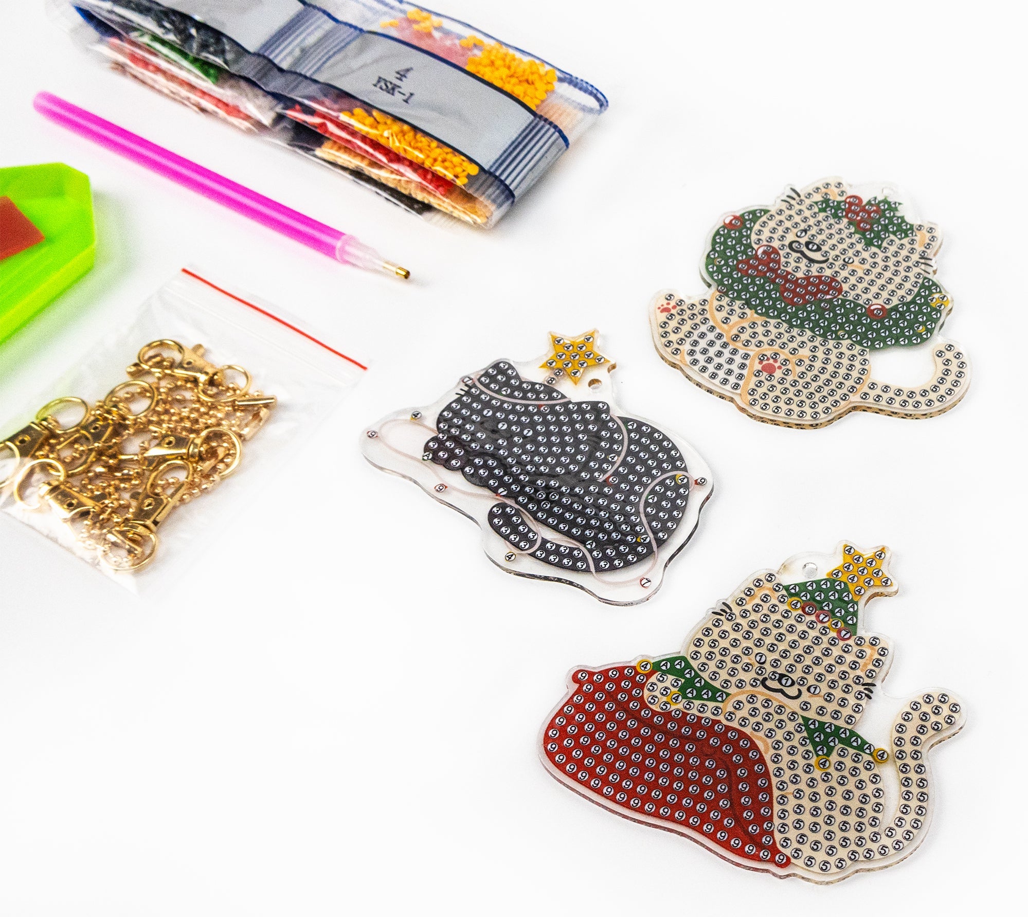 Decorative keychains with rhinestone designs on a white surface with craft supplies.
