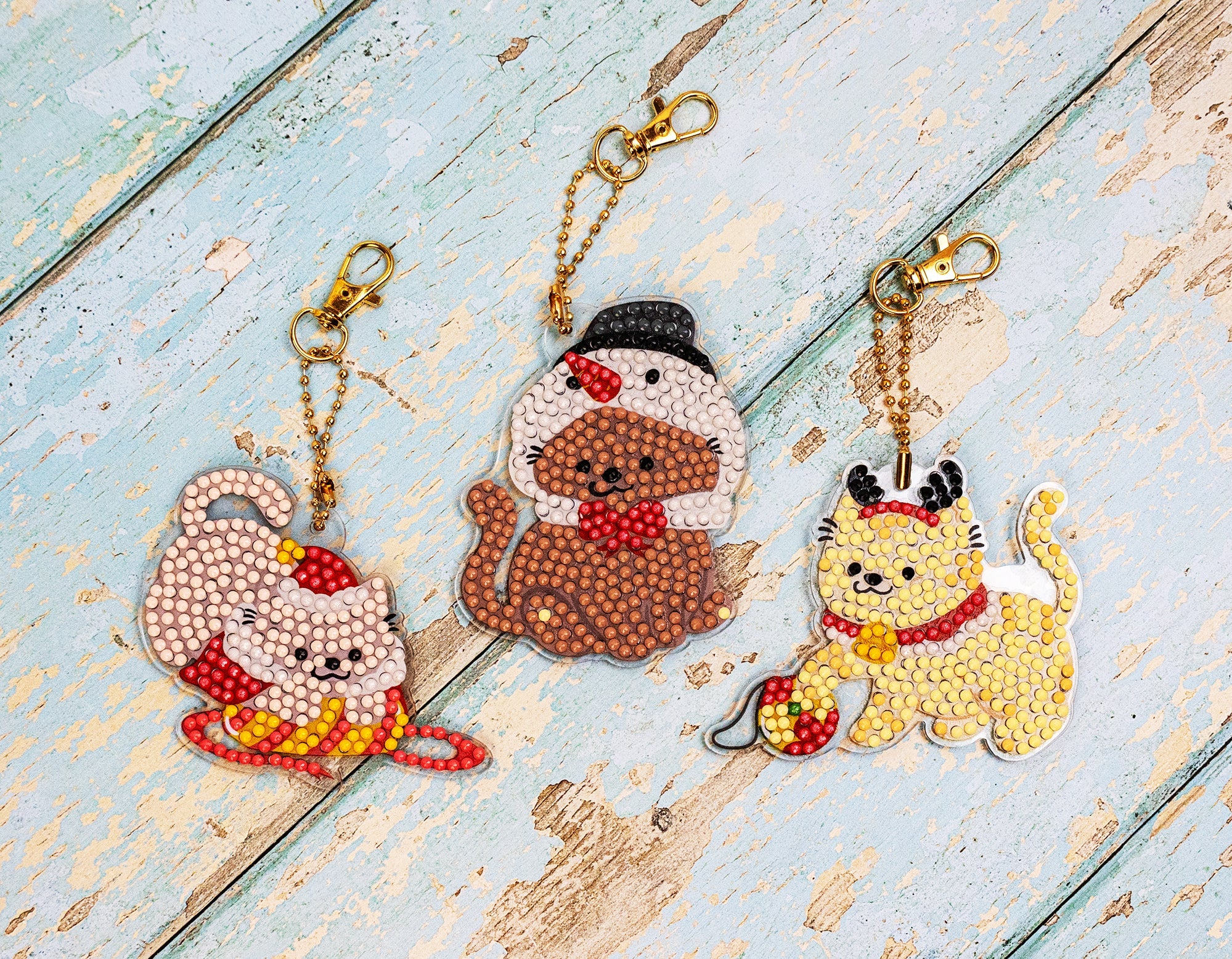 Three decorative keychains shaped like a cat, a bear, and a dog on a wooden surface.