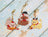 Three decorative keychains shaped like a cat, a bear, and a dog on a wooden surface.