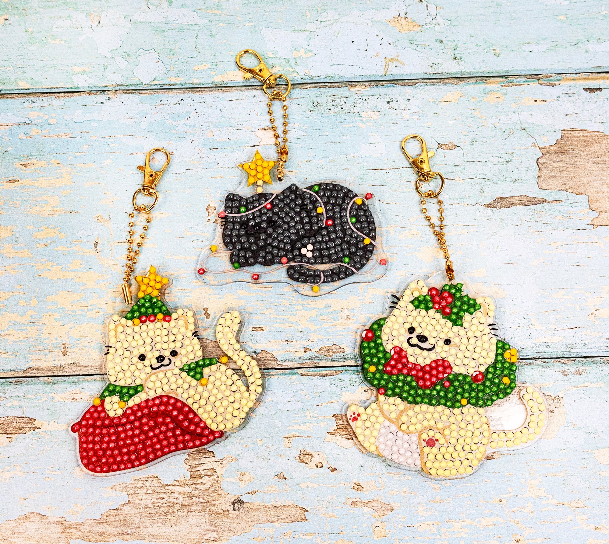 Three cat-themed keychains on a wooden surface