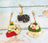 Three cat-themed keychains on a wooden surface