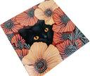 Black cat with orange eyes peeking out from a decorative surface with floral patterns