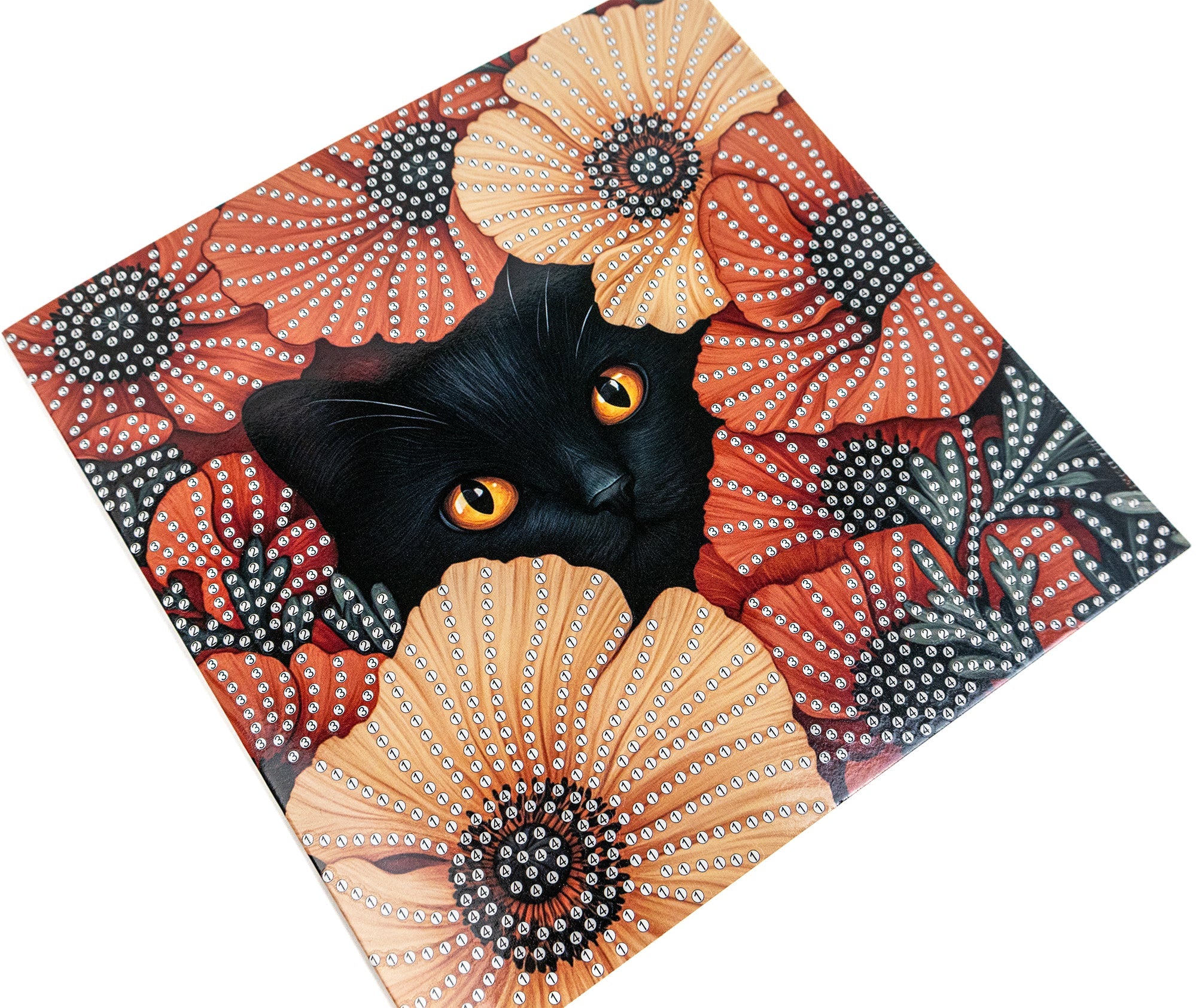 Black cat with orange eyes peeking out from a decorative surface with floral patterns