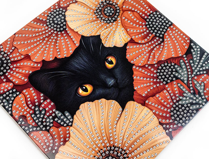 Black cat with orange eyes surrounded by decorative flowers with rhinestones on a white background