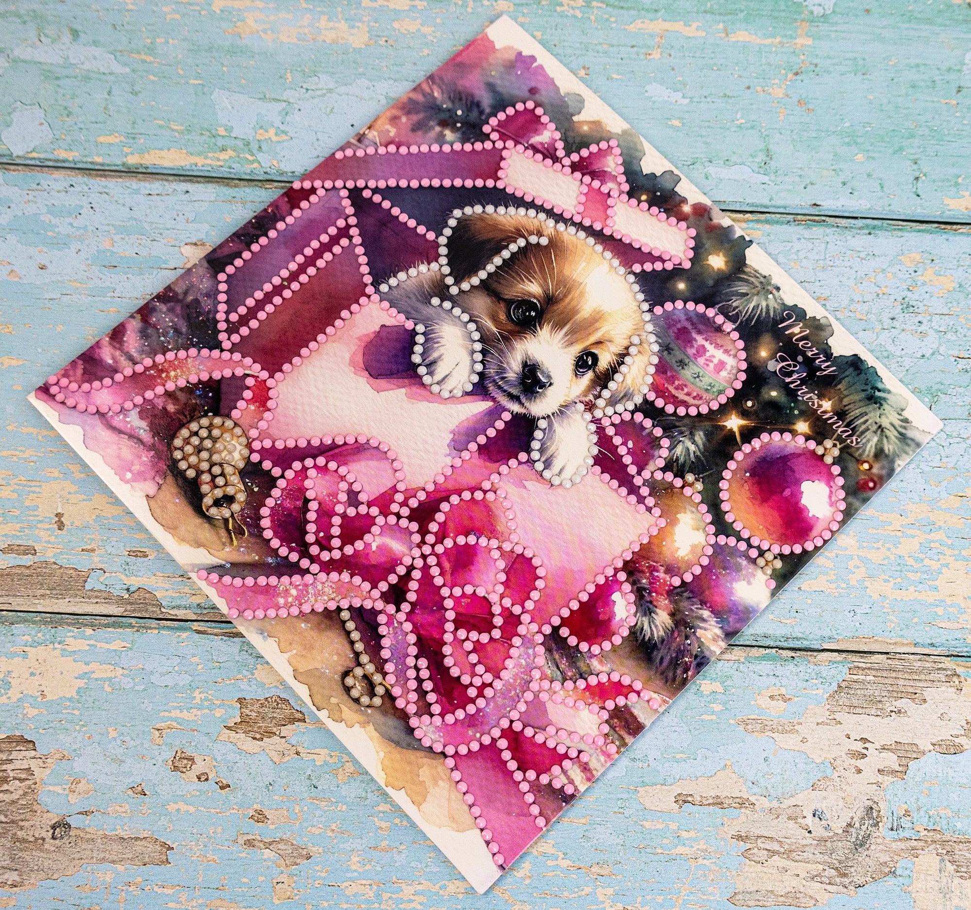 Card with a puppy design featuring pink bows and beads on a wooden surface