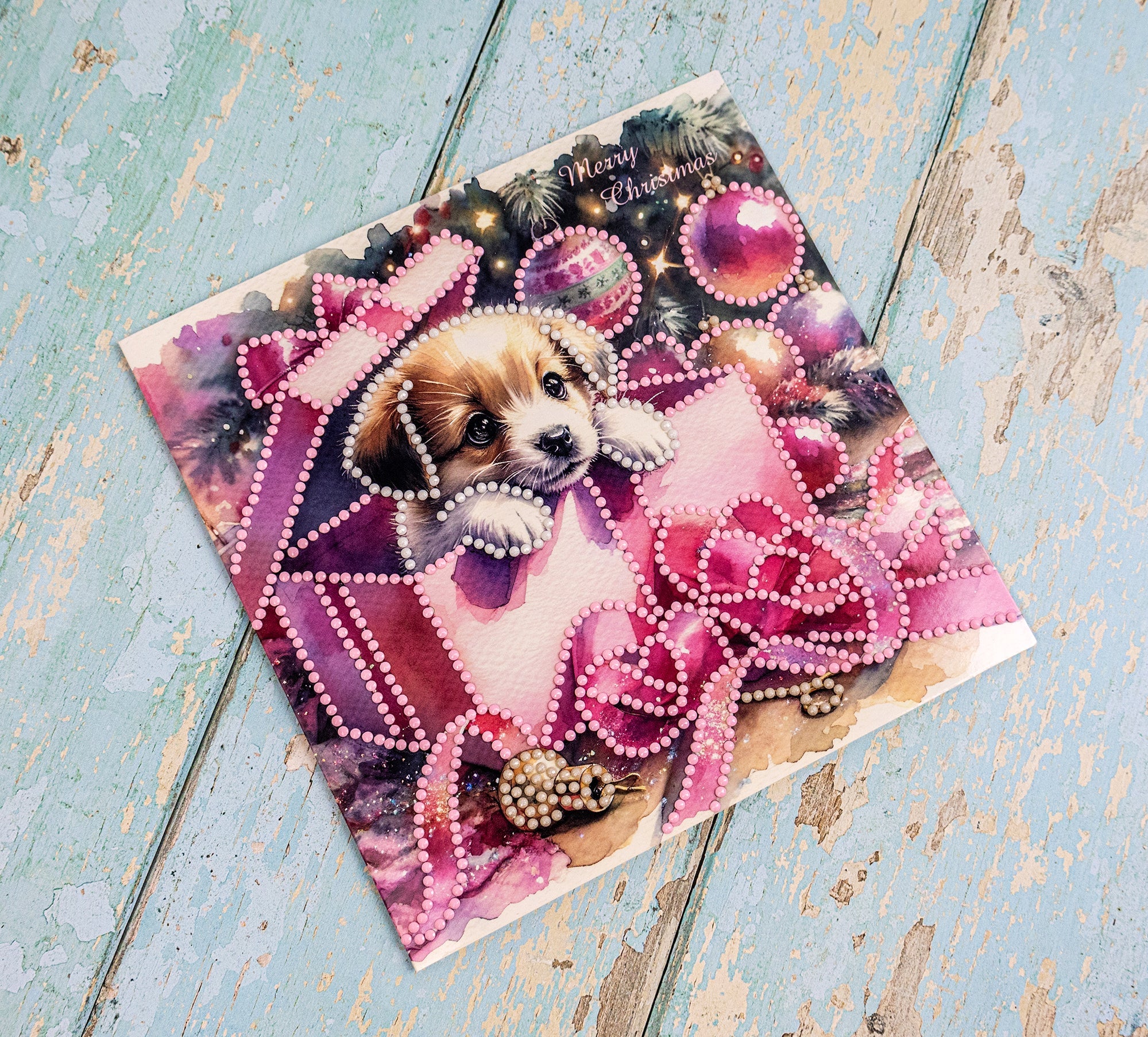 Vintage-style Christmas card with a puppy and decorative elements on a wooden surface.