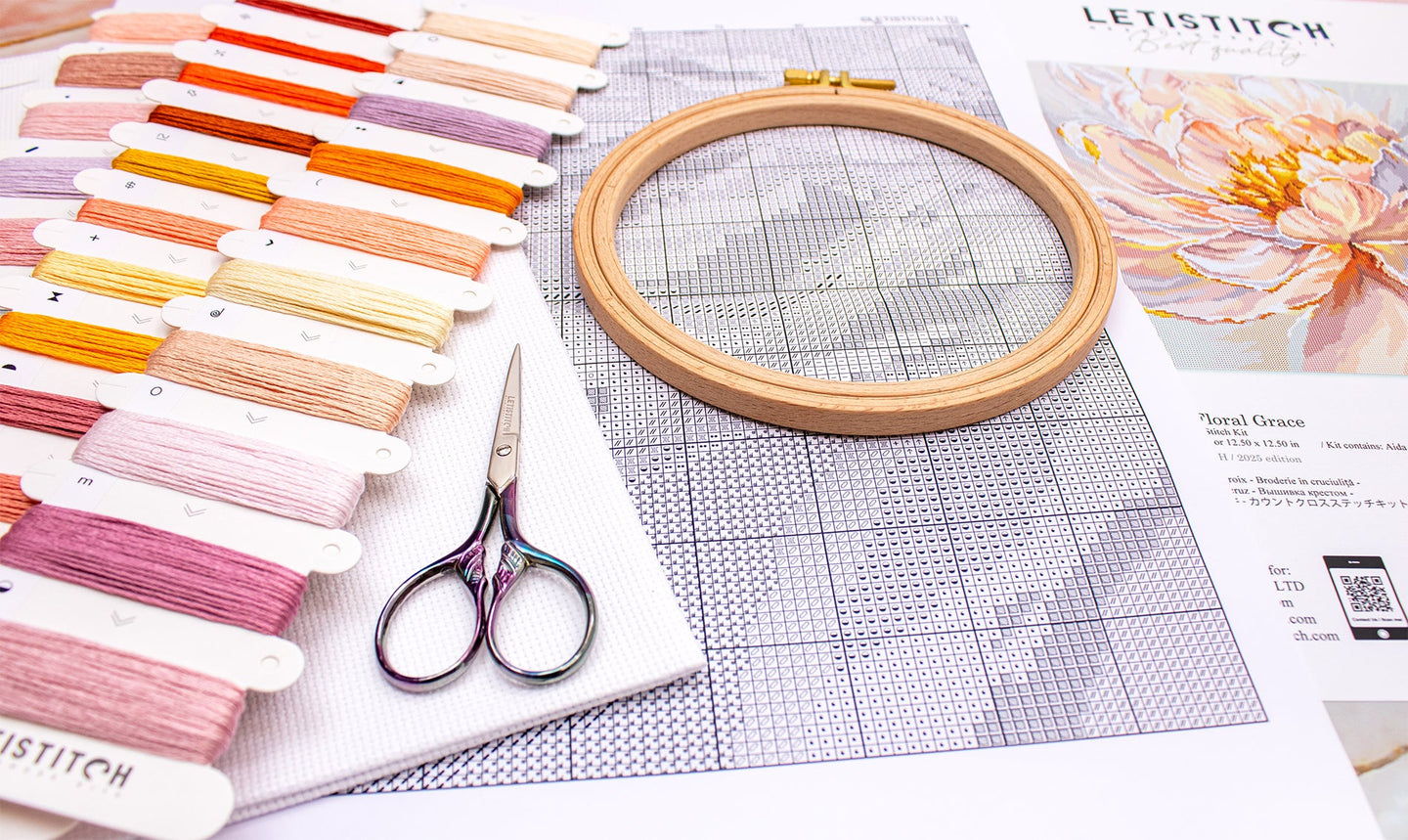 Embroidery hoop, threads, scissors, and a pattern sheet on a table.
