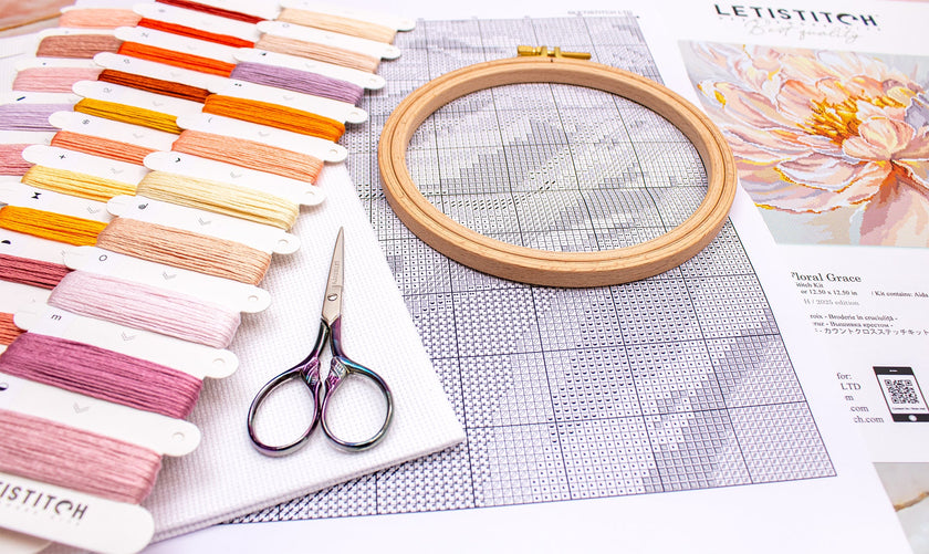 Embroidery hoop, threads, scissors, and a pattern sheet on a table.