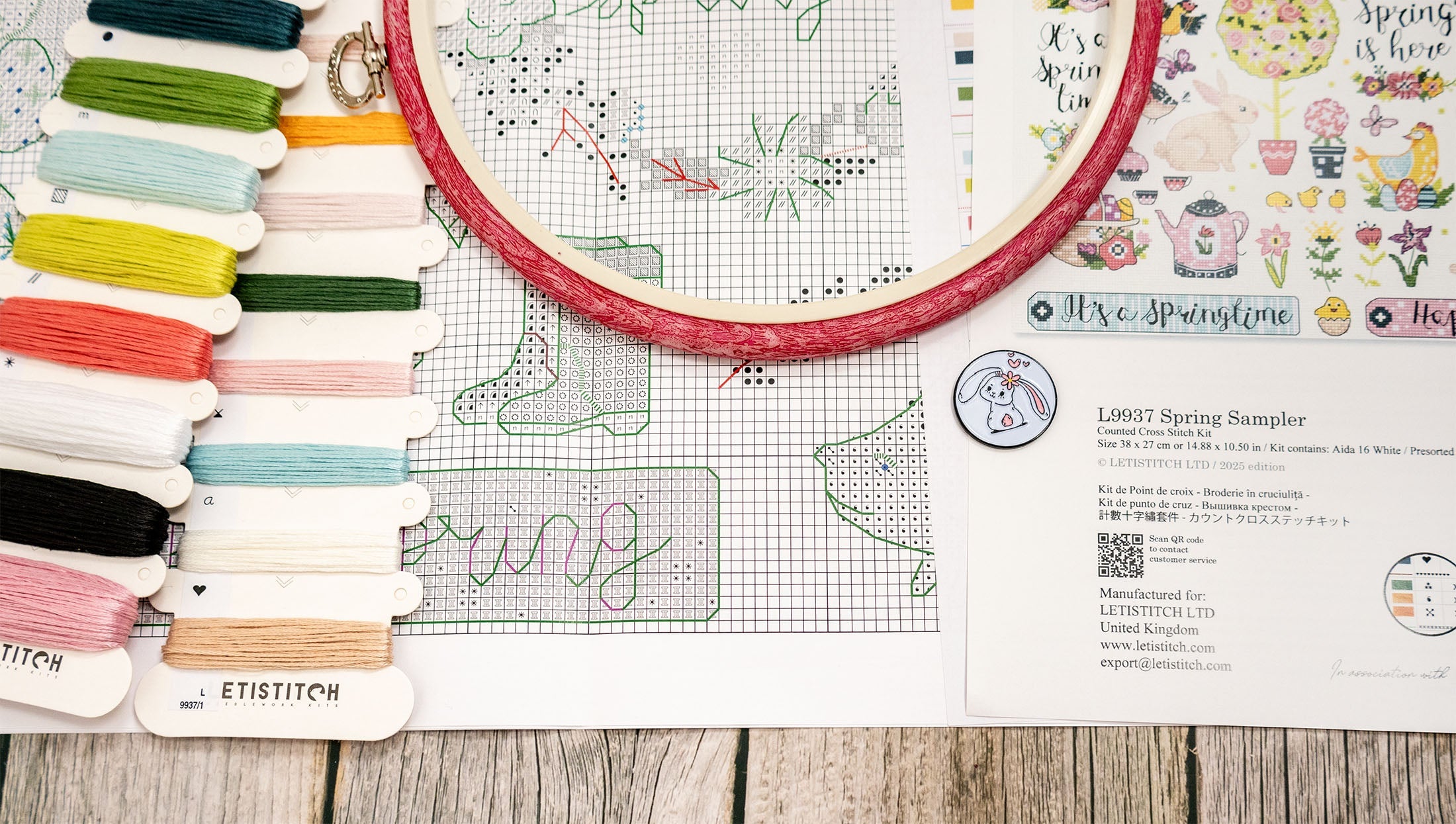 Embroidery hoop with colorful threads and a pattern sheet on a wooden surface