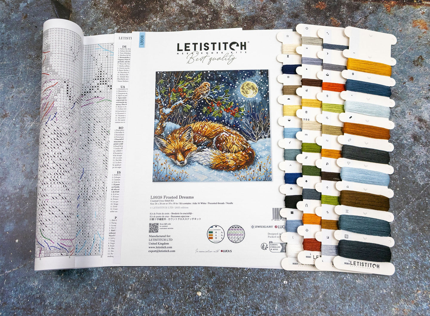 Cross-stitch pattern book with a fox illustration and color swatch on a textured surface