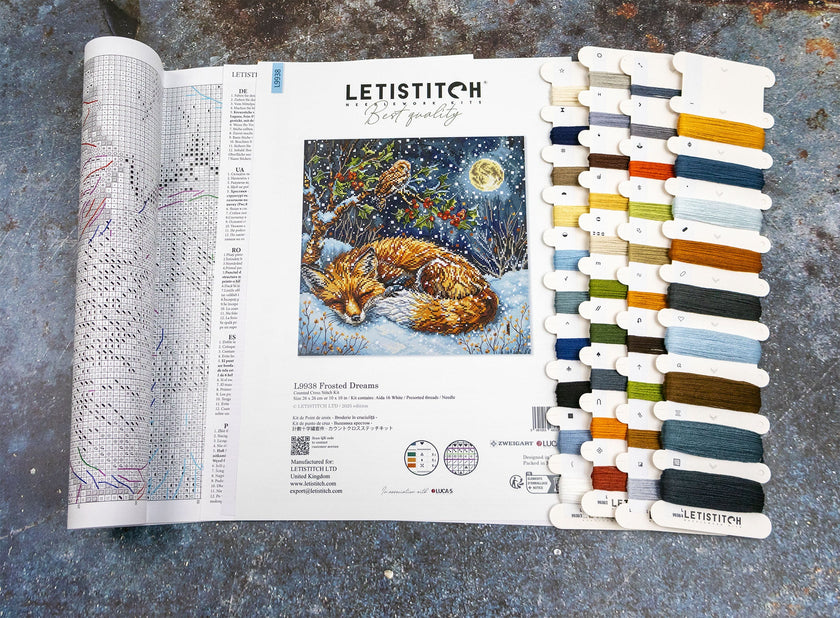 Cross-stitch pattern book with a fox illustration and color swatch on a textured surface