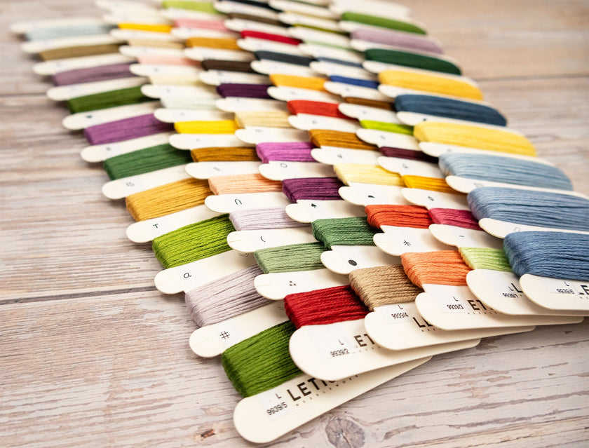 Color swatch card with various sewing threads on a wooden surface