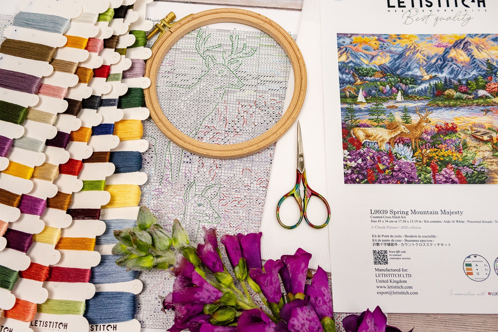 Embroidery hoop with cross-stitch pattern, scissors, and color swatch on a table.