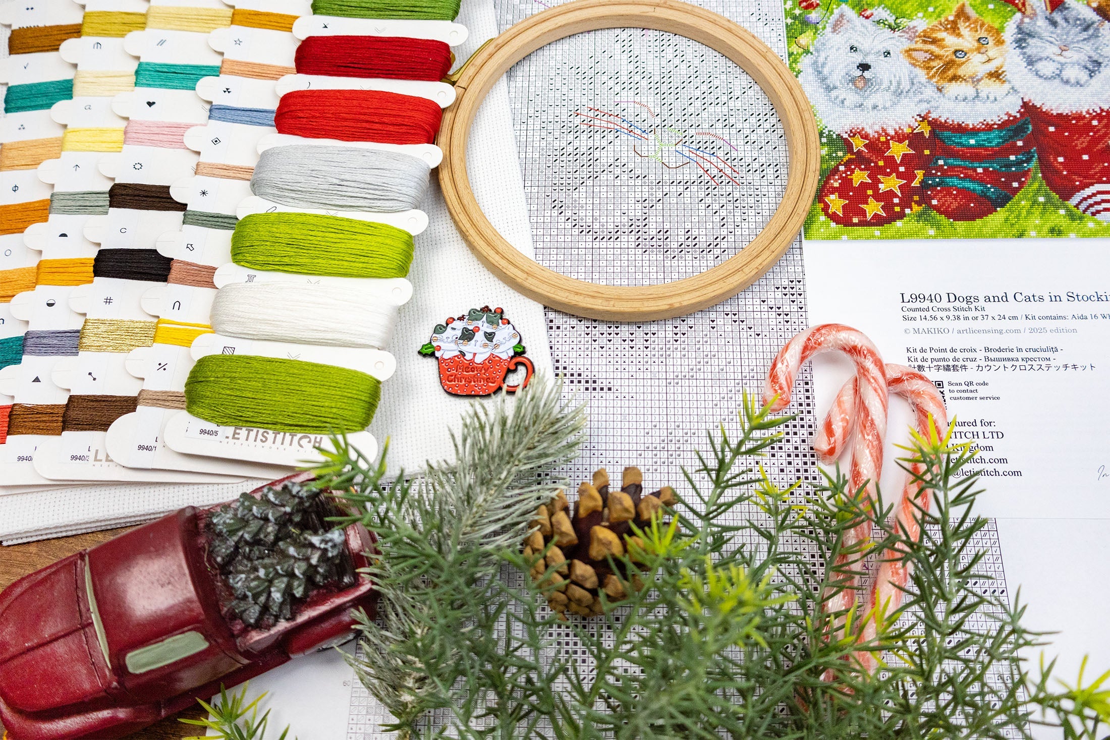 Cross-stitching materials including a hoop, threads, and a partially completed cross-stitch design on a festive-themed fabric.