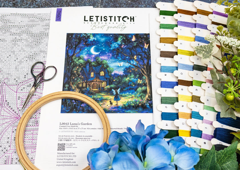 Embroidery kit with hoop, thread, scissors, and pattern sheet on a table.