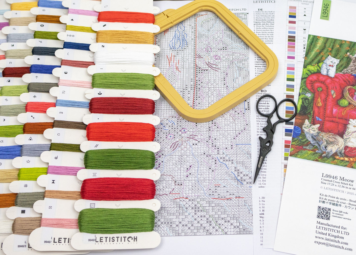 Embroidery hoop, threads, scissors, and cross-stitch pattern on a table.