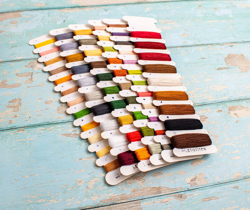 Colorful thread spools on a wooden board with a rustic background