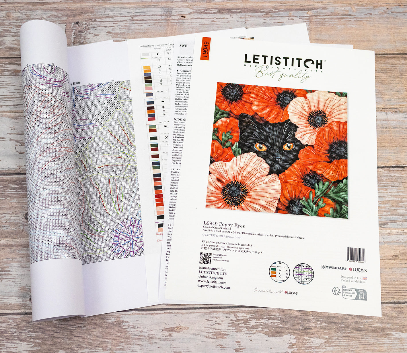 Embroidery pattern with a black cat and orange flowers on a wooden surface