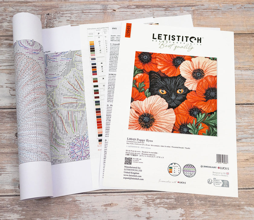 Embroidery pattern with a black cat and orange flowers on a wooden surface