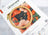 Embroidery hoop with a black cat design on floral fabric, placed on a Letistitch embroidery kit packaging.