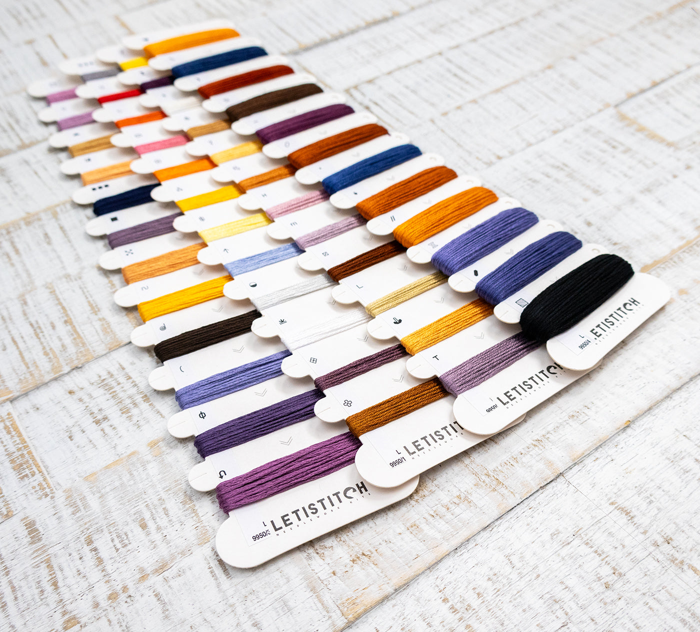 Set of embroidery floss colors on a wooden surface with 'LetiStitch' branding.