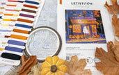 Embroidery kit with Halloween-themed design, threads, and leaves on a flat surface