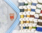 Cross-stitch hoop with colorful threads and a partially completed design.