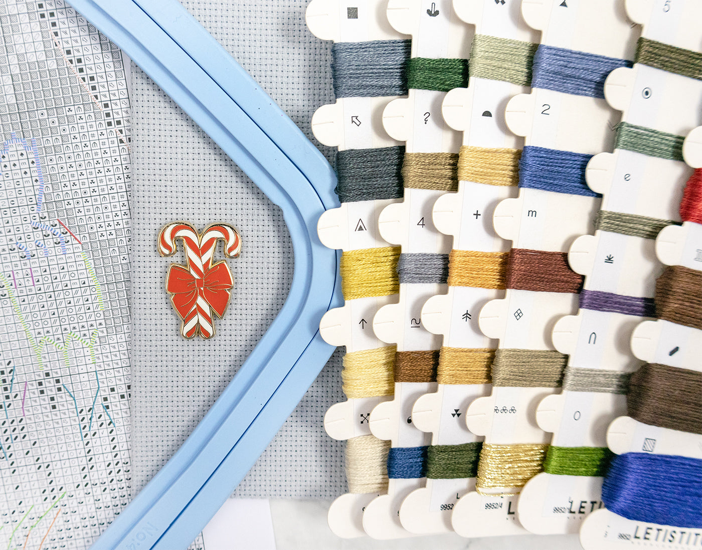 Cross-stitch hoop with colorful threads and a partially completed design.