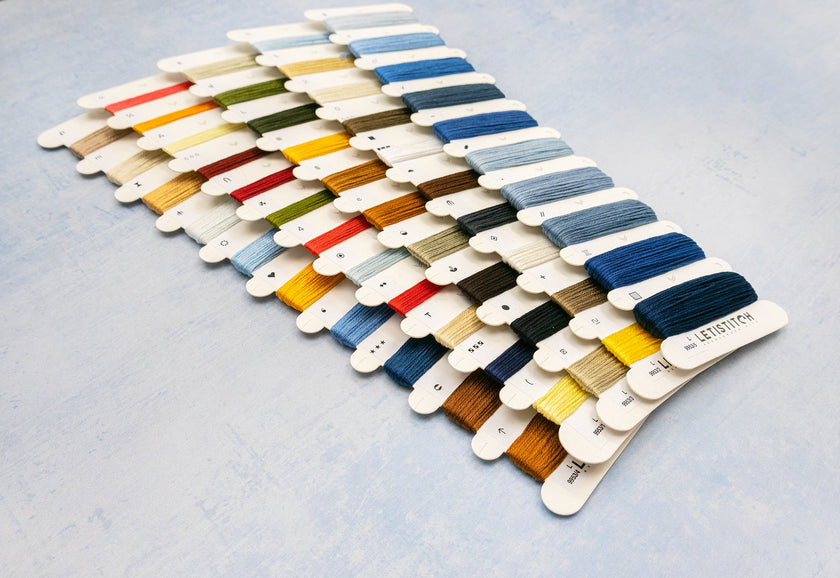 Color swatch card with various embroidery thread colors on a light gray background