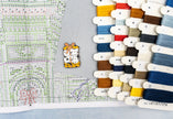 Collection of colorful thread spools and a cross-stitch pattern on fabric.