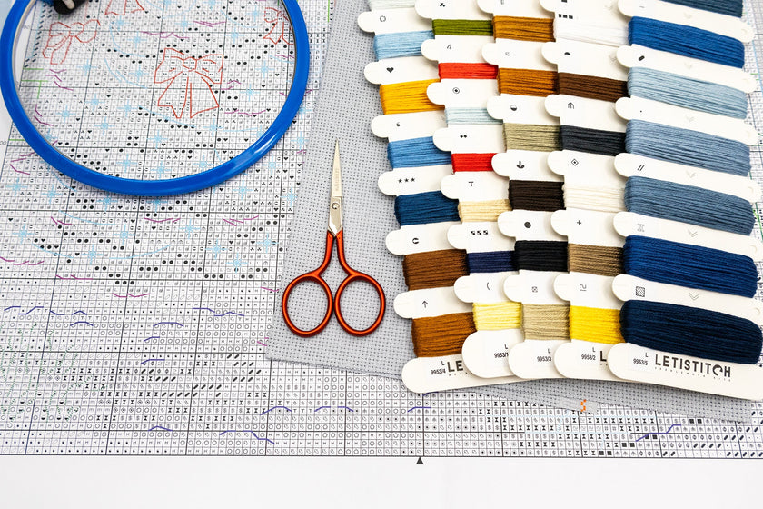 Embroidery hoop, scissors, and color swatch on a cross-stitch chart