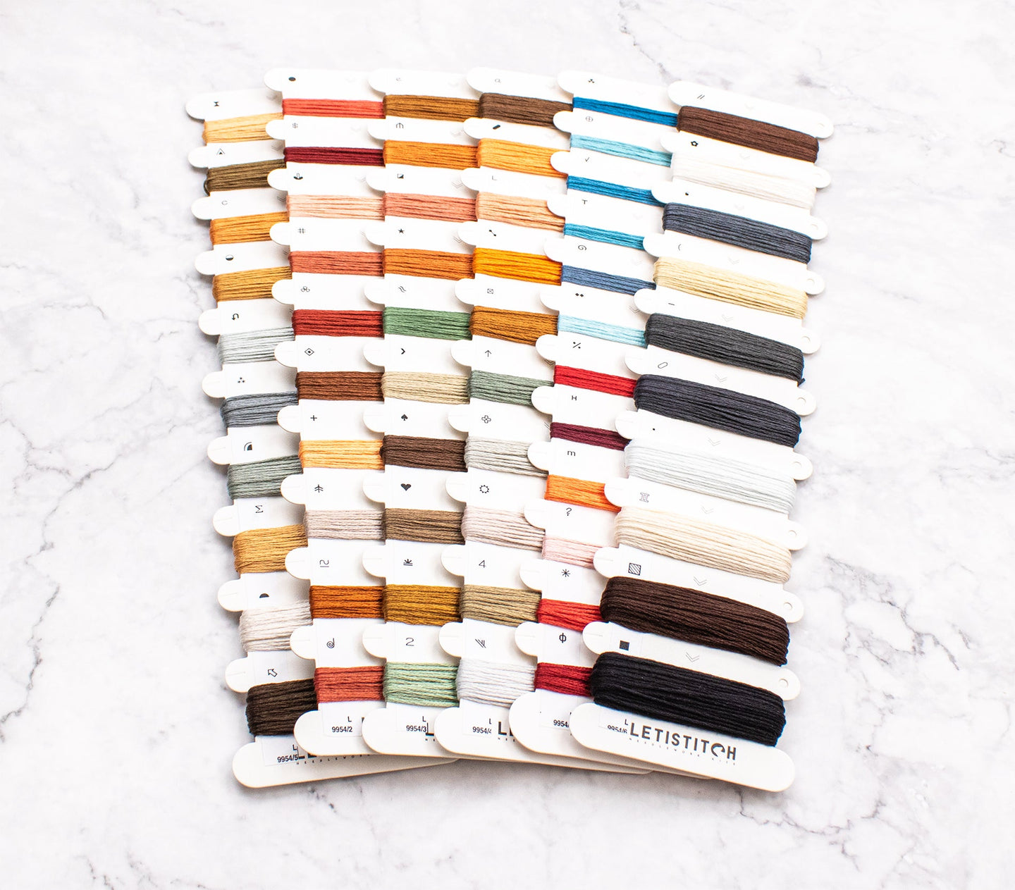 Color swatch card with embroidery floss on a white marble surface
