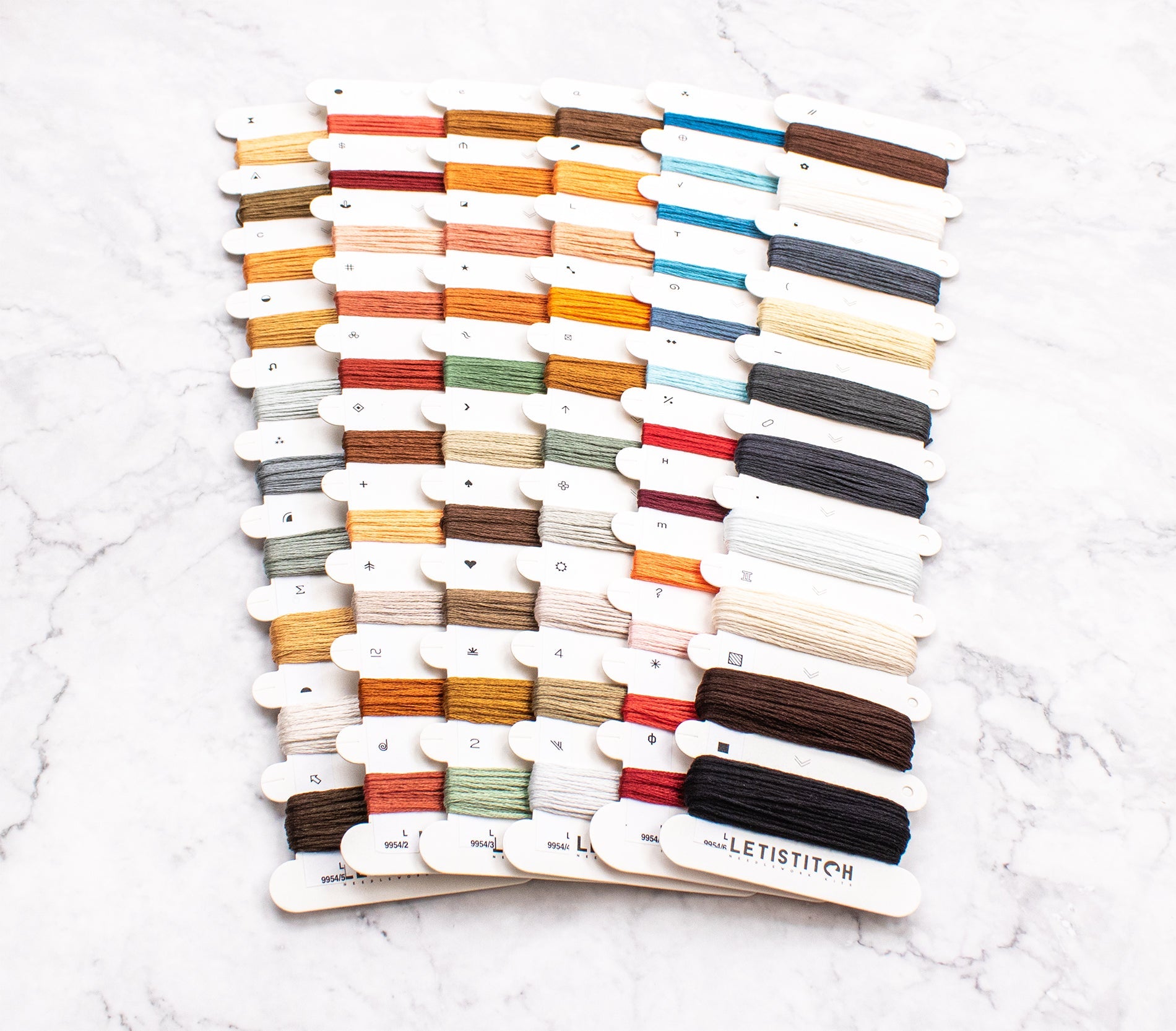 Color swatch card with embroidery floss on a white marble surface