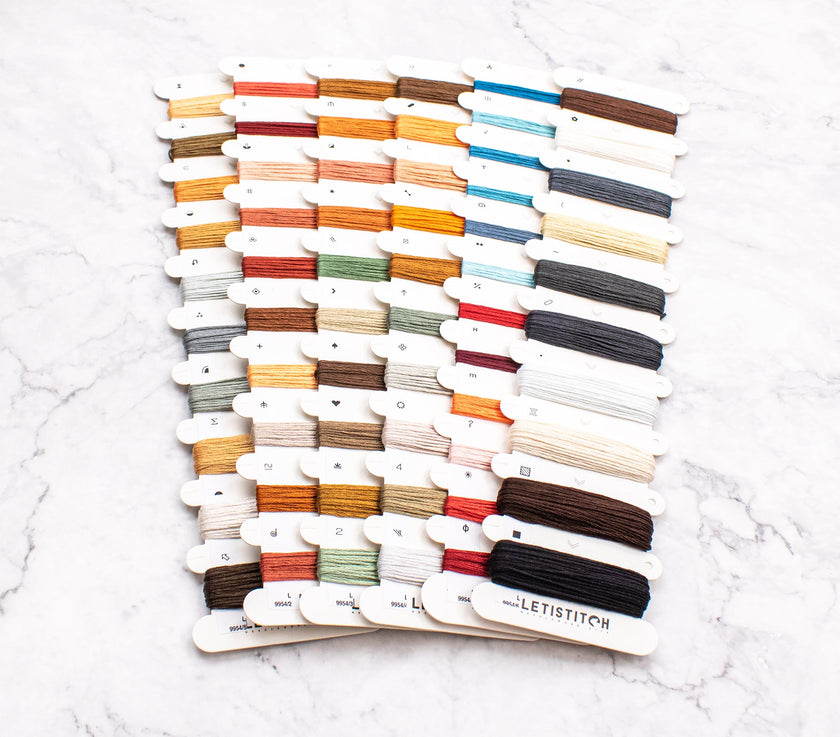 Color swatch card with embroidery floss on a white marble surface