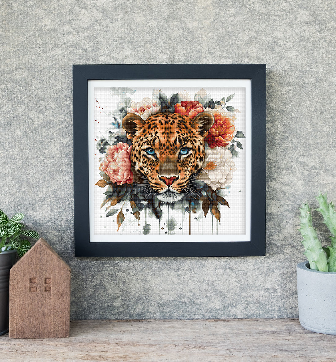 Framed artwork of a leopard's head surrounded by flowers on a textured wall.