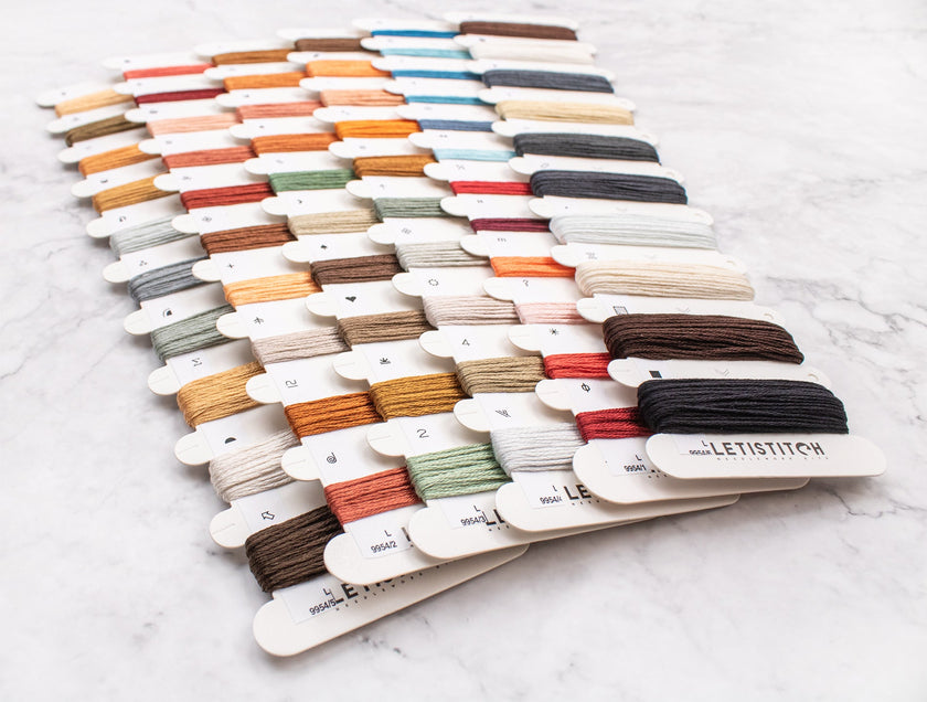 Collection of colorful embroidery threads on a white marble surface