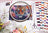 Embroidery hoop with a tiger design surrounded by thread spools and scissors on a magazine page.