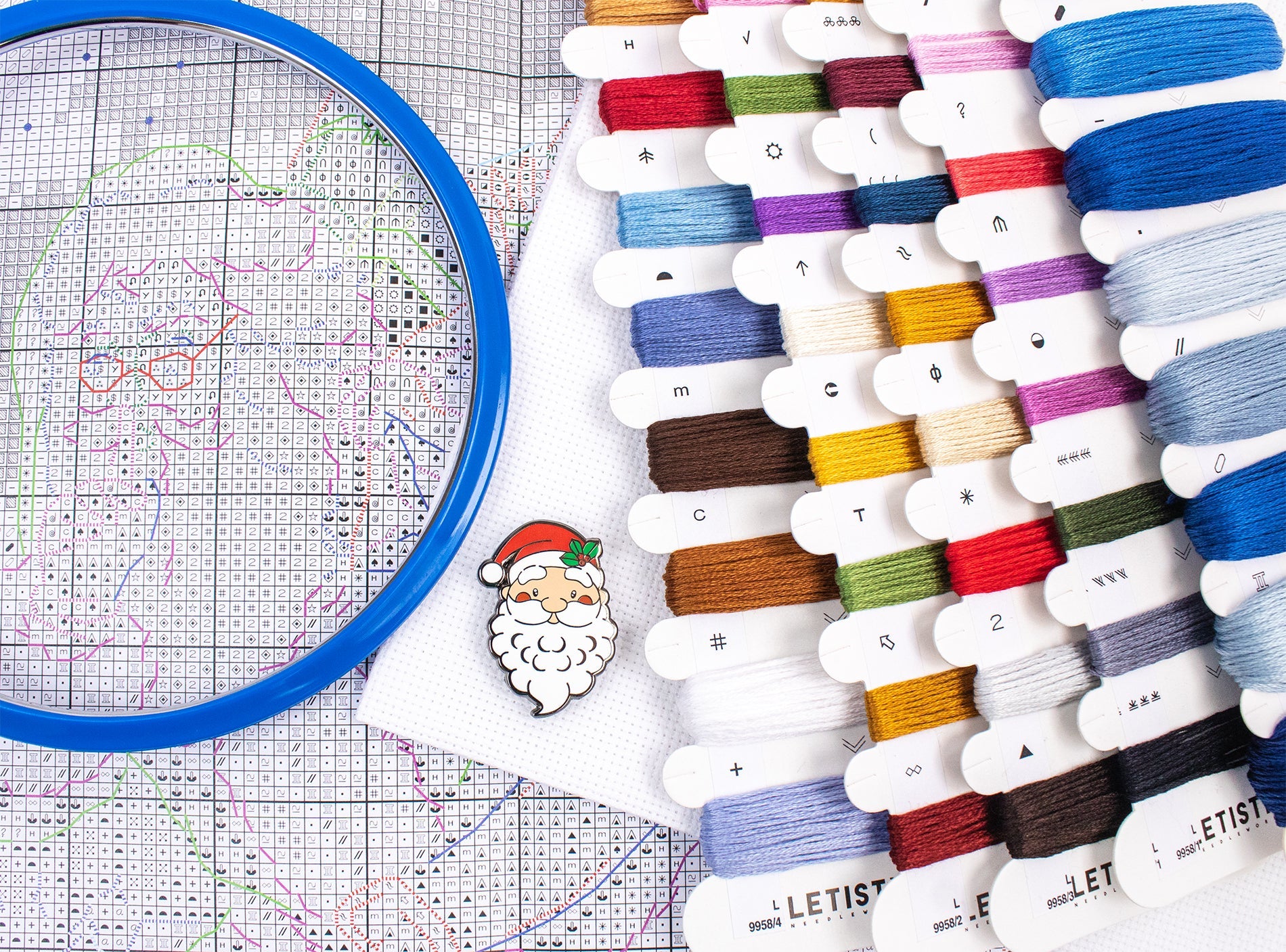 Embroidery hoop with colorful thread spools on a cross-stitch chart
