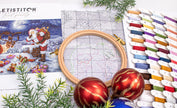 Embroidery hoop, cross-stitch pattern, and Christmas ornaments on a table.