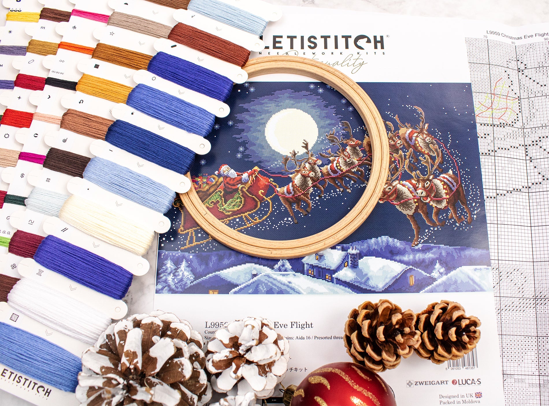 Embroidery kit with thread colors, an embroidery hoop, and a Christmas-themed design on a white background.