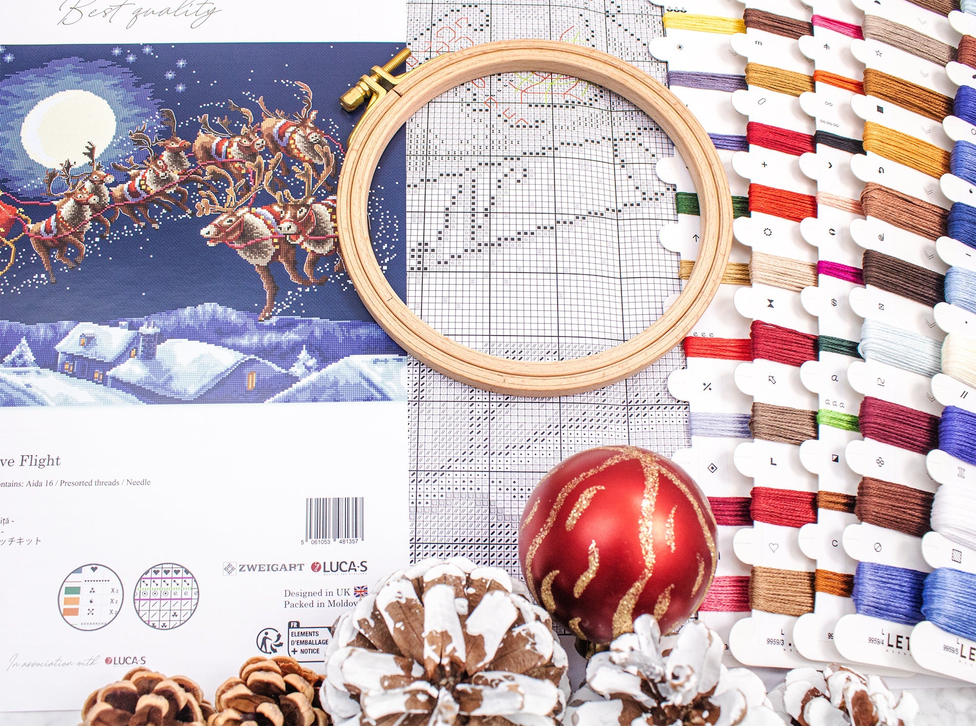 Embroidery kit with cross-stitch pattern, hoop, thread spools, and Christmas-themed decorations.
